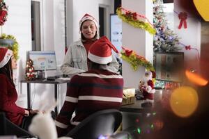 Director having nice talk with staff members, discussing year end business matters before festive holiday season. Management executive chatting with workers in Christmas decorated workspace photo