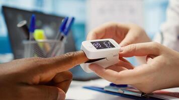 Doctor with expertise uses an oximeter to measure the oxygen saturation for a patient during examination, diagnostic tools for support. Consulting man with professional oximetry readings. Camera B. photo