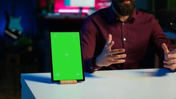 Happy influencer in studio filming chroma key tablet review for tech enthusiasts. Joyful media star hosts technology internet show, unboxing isolated screen digital portable device, camera A close up photo
