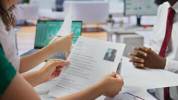 Job candidate hands over his CV to team of HR professionals in order to start interview, focusing on the experience in the resume. Discussing potential career development. Close up. Camera B. photo