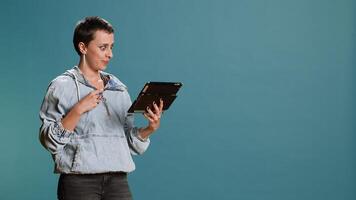Stylish person doing online shopping with her credit card in studio, feeling happy spending money on what she likes. Catching seasonal promotions for placing multiple orders, e commerce. Camera B. photo