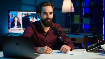 Smiling media star arriving in studio, using professional recording equipment to film vlog channel intro for online streaming platforms. Cheerful man starting stream, greeting viewers, camera A photo