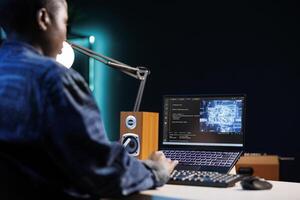 Professional female developer manages neural network at desk, working with code on laptop. Over the shoulder shot of african american freelancer developing cyber security, creating secure database. photo