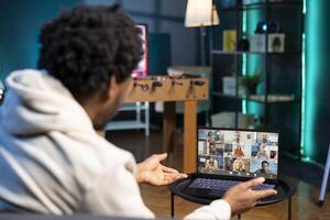 Management executive discussing company matters with remotely working multiethnic team during videoconference meeting. Manager teleworking in living room, discussing project progress with workers photo