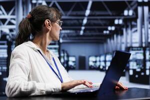 Old proficient electrician inside high tech facility providing computing resources needed for AI to process extensive datasets for training. Server room storing data used for machine learning photo