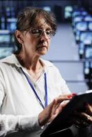 Certified technician preparing server rackmounts recovery plan, monitoring data center energy consumption across parts, making sure sensors are functioning errorlessly, doing annual disk checks photo