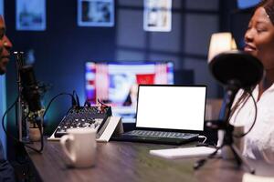 Detailed view of laptop featuring blank chromakey screen for talk show promotion. Selective focus on portable computer displaying an isolated white screen for advertising an online streaming platform. photo