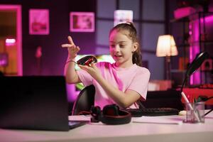 Gen Z media star in studio reviewing gaming mouse in front of camera in personal studio. Cheerful kid filming electronics haul, showcasing wired computer peripheral to audience photo