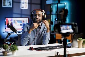 African American man assessing headphones, expressing dissatisfaction with subpar audio quality. Content creator shooting for online channel, displeased with audio device performance photo