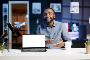 Influencer in home studio using recording tech to capture live broadcast, reviewing mockup laptop. Online show host filming electronics haul, presenting isolated screen notebook for viewers photo