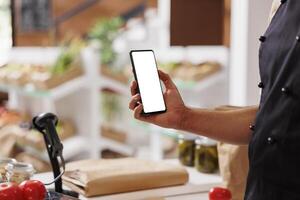 Caucasian salesperson grasping a tablet displaying blank chromakey template for advertisement of eco friendly food store. Perfect digital mockup for customer service and packaging tools. photo
