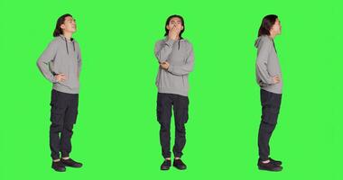 Young guy feeling sleepy and yawning after not getting enough sleep, posing with fatigue over full body greenscreen backdrop. Asian person being extremely tired and exhausted, falling asleep. photo