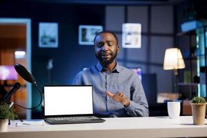 African american reviewer looking at mockup laptop, unsure how to rate it after finding pros and cons. Tech content creator presents fans advantages and disadvantages of isolated screen notebook photo