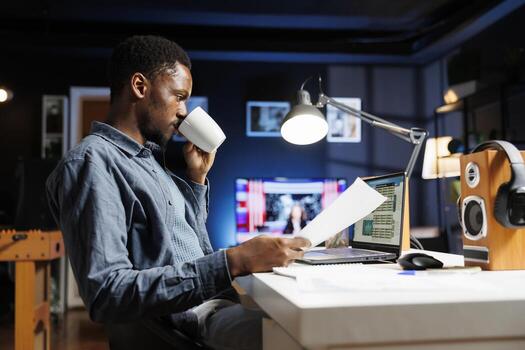 Financial advisor reading monthly balance on papers, studying archived records before making another global investment. African american expert working with online statistics and records. photo