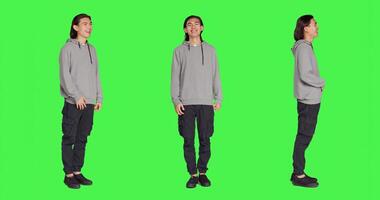 Cheerful male model laughing in studio, posing and being positive against full body greenscreen backdrop. Asian man smiling in studio, showing amusing funny expressions, relaxed guy. photo