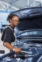 Mechanic in car service picks torque wrench from work station bench, using it to tighten bolts after replacing fuel tank. Licensed BIPOC garage worker uses professional tools to fix client automobile photo