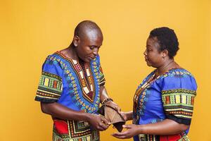 African american man looking in open wallet with no money inside while having conflict with wife. Annoyed woman showing empty purse to husband while discussing financial trouble photo
