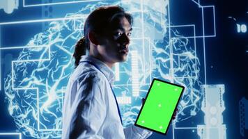 Tech savvy IT practitioner using green screen tablet to implement artificial intelligence parallel processing. Proactive inspector oversees chroma key device enabling AI to do machine learning photo