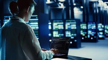 Certified admin running code and programming on laptop, troubleshooting and upgrading server hub equipment designed to accommodate rackmounts, networking systems and storage arrays photo