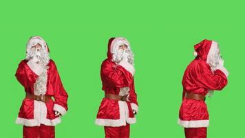 Discreet saint nick does hush sign in studio, expressing secrecy with confidential symbol on greenscreen backdrop. Santa claus man in suit showing mute gesture, silence concept. photo