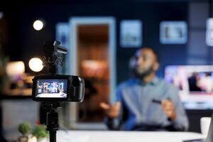 Focus on production camera gear used by content creator doing ASMR for fans. Online show host in blurry background using professional microphone to whisper and put viewers to sleep photo