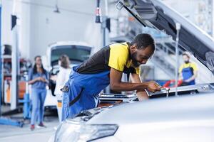 Engineer expertly examines car alternator using torque wrench, ensuring optimal automotive performance and safety. Certified garage mechanic conducts annual vehicle checkup photo