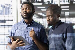 Team of office clerks working together on finishing project before impending deadline, auditing financial payroll reports in office. Teamworking coworkers looking at tablet, brainstorming ideas photo