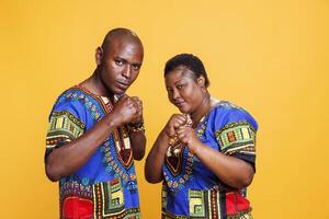 Serious african american couple standing in fighting pose with clenched fists and looking at camera. Confident man and woman fighters showing strength and boxing portrait photo