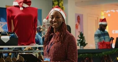 Portrait of cheerful manager browsing through festive clothing display in Christmas shopping store, making sure clothes are ready for customers during winter holiday bargains season photo