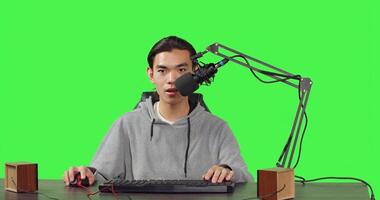 Asian man streamer broadcasting gameplay while he is sitting at desk and playing online action videogames with friends. Young blogger recording live stream at pc with microphone. photo