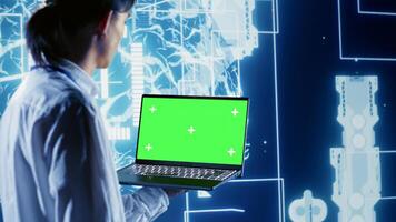 Precise admin using green screen laptop to write artificial intelligence script code in startup workplace. Skillful professional doing maintenance work in data center, updating AI systems photo