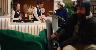Personnel guiding asian guest and aiding in going skiing on alpine ski slopes. The hotel concierge gives advice to woman regarding mountain resort intense wintertime activity. photo