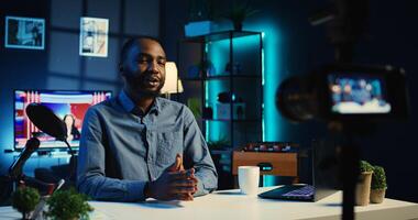 Smiling influencer in cozy home using professional camera to film live broadcast for online streaming platforms. Internet star hosts q a session with audience members using recording equipment photo