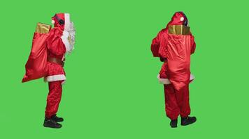 Modern character listening to music in studio, dressed as santa claus and dancing on fun songs with headset. Man cosplay saint nick dance and sing using audio headphones, greenscreen. photo
