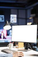 Remote worker looking at white template on pc monitor, sitting at home and using empty computer layout screen. African american freelancer checks isolated blank display at his workstation. photo
