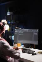 Traditional Middle Eastern developer compiles code on desktop computer, showcasing expertise in programming, algorithms, and software development. Selective focus on pc monitor displaying source code. photo