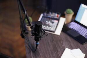 Home recording setup for a radio show or podcast, featuring a microphone, laptop, and sound equipment. Top view of desk containing professional mic and sound mixer, ideal for home studio. photo