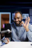 African american content creator using smartphone to film vlog channel intro for online streaming platforms. Media star greets fanbase, presenting today topic, recording with phone photo