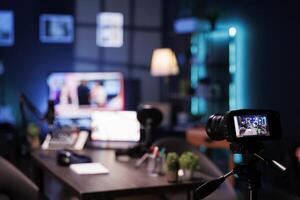 There is no one in the studio using professional microphone and headphones for an online radio interview. Digital camera on tripod captures empty desk with streaming equipment for broadcasts. photo