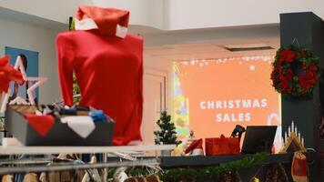 Led display advertisement in xmas decorated clothing store announcing Christmas sales. Promotional animated billboard inviting customers looking for bargains in festive adorn shop photo