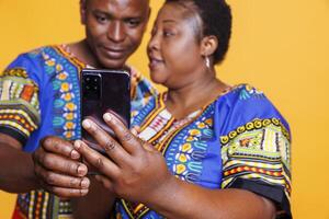 African american couple holding smartphone in hand and using application together. Man and woman spouse scrolling social media and reading message on mobile phone closeup photo