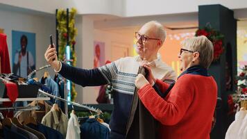 Happy senior couple shopping for clothes while on internet videocall with nephew, asking for advice on picking perfect xmas present before festive family dinner visit during festive holiday season photo