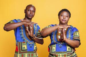 Confident man and woman showing timeout gesture with hands and looking at camera. Serious african american couple indicating stop signal, asking to take break studio portrait photo