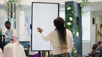 Customer in high tech thrift shop using digital isolated screen to find ideal outfit. BIPOC client in cheap second hand clothing store doing shopping using augmented reality kiosk photo