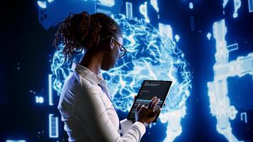Seasoned IT contractor programming scripts on tablet, employing AI machine learning. Proficient worker manipulating lines of code for artificial intelligence applications development photo