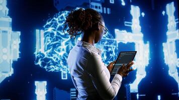 African american scientist programming scripts on tablet, employing AI machine learning infrastructure. Licensed employee manipulates lines of code for artificial intelligence applications development photo