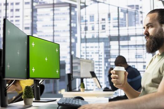 Employee looking at mockup PC monitor, drinking coffee, checking data needed for finding business insights and finishing project task. Man analyzing data on isolated screen computer, enjoying beverage photo