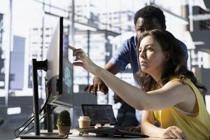 African american supervisor asking accountant to show him business project tasks progress in modern office during nightshift. Management executive overseeing employee working on computer photo