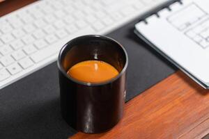 Black Coffee Mug on Desk with Keyboard and Notebook photo