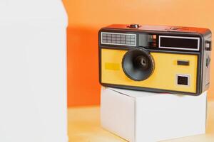 Retro Camera on Display Against Vibrant Orange Background photo